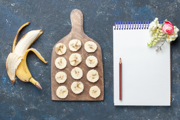 Free photo top view of fresh yellow banana sweet and delicious peeled out and sliced with notepad on dark, fruit berry sweet vitamine health