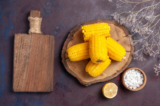 Top view fresh yellow corns with lemon on dark surface corn food raw fresh snack