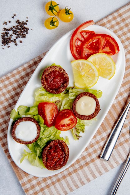 Top view of fried balls with mushrooms and tomatoes