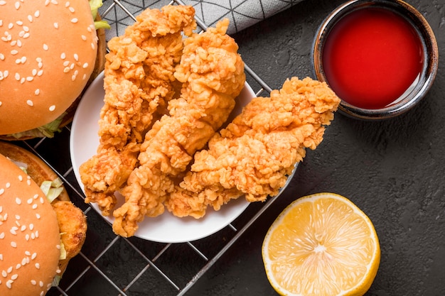 Top view fried chicken and burgers on tray  with sauce and lemon