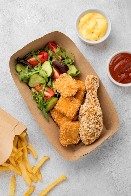 Top view of fried chicken nuggets and french fries with sauces