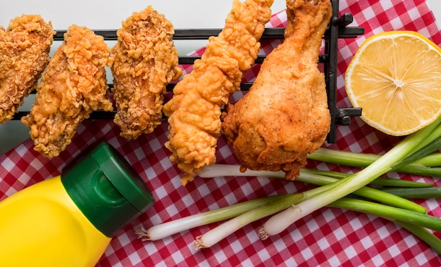 Free photo top view fried chicken pieces on tray with fries, sauce and lemon