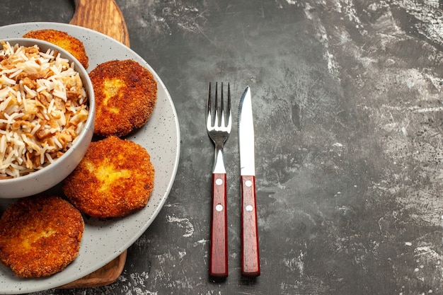 Top view fried cutlets with cooked rice on a dark desk dish meat rissole