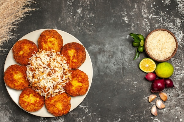 Free Photo top view fried cutlets with cooked rice on dark surface food dish meat rissole