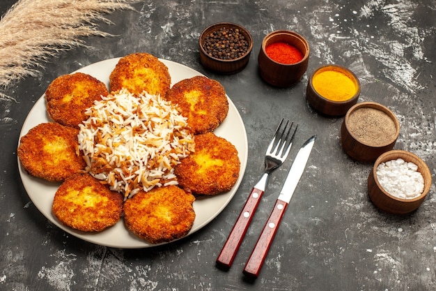 Free photo top view fried cutlets with cooked rice and seasonings on dark desk photo food meat dish