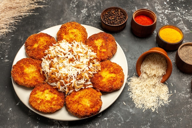 Free photo top view fried cutlets with cooked rice and seasonings on a dark surface food meat dish