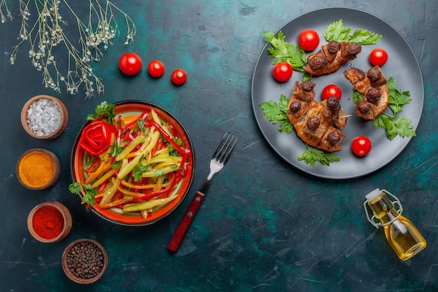 Top view fried meat slices with olive oil salad and seasonings on dark-blue desk vegetable food meat health meal