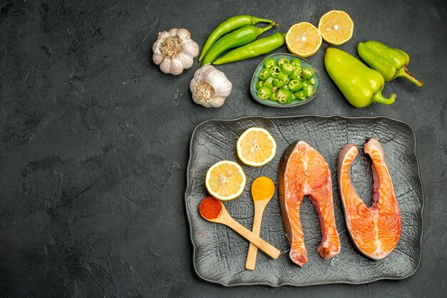 Top view fried meat slices with peppers and lemon on dark background