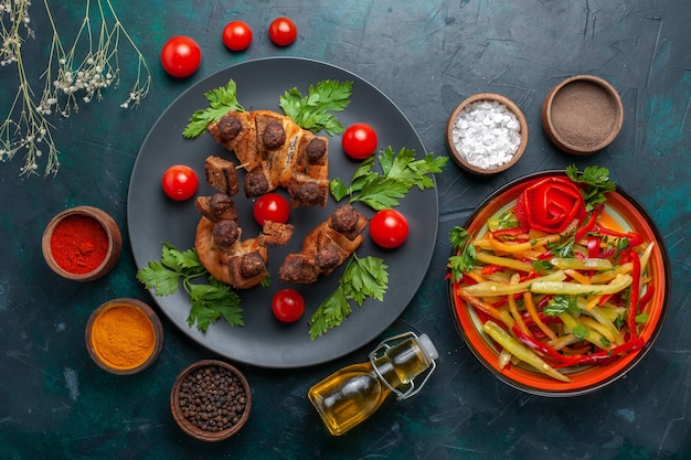 Top view fried meat slices with vegetables and seasonings on the dark blue surface vegetable meal food meat dinner health