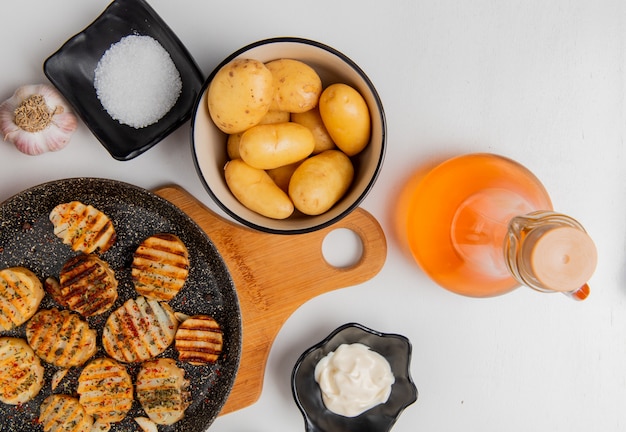 Top view of fried potato slices in frying pan on cutting board