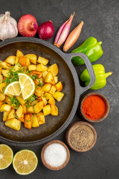 Free Photo top view fried potatoes inside pan with different seasonings and vegetables on dark background