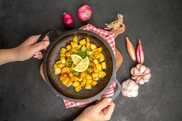 Top view fried potatoes inside pan with lemon on a dark background