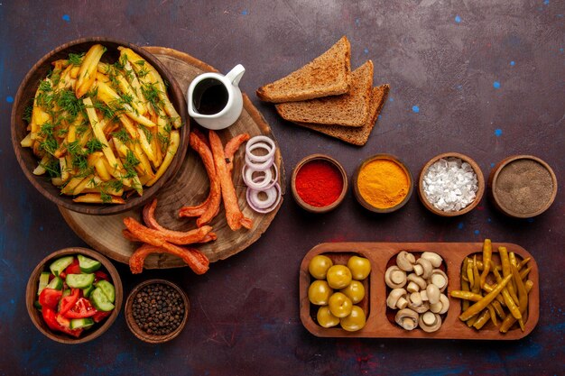 Top view fried potatoes with seasonings bread loafs and different vegetables on dark desk