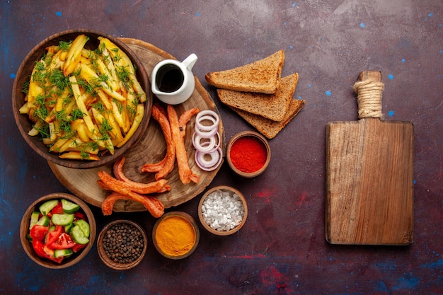 Top view fried potatoes with seasonings bread loafs and different vegetables on the dark surface