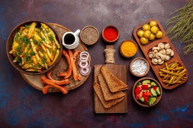 Top view fried potatoes with seasonings and different vegetables on dark surface