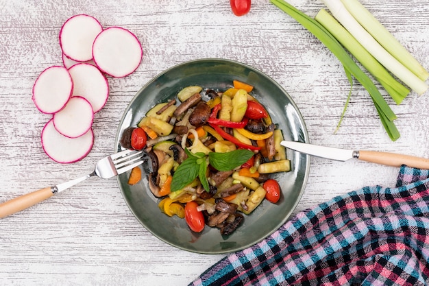 Free Photo top view fried vegetable salad mushroom cherry tomato red pepper yellow pepper with knife and fork