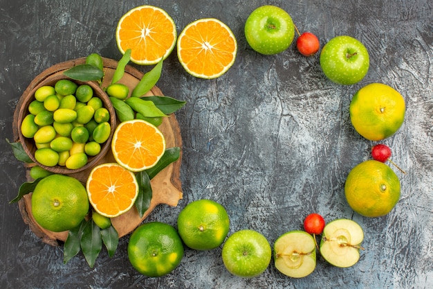 Top view from afar apples citrus fruits on the board apples with leaves cherries