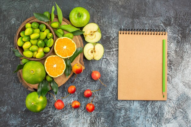 Top view from afar fruits the appetizing berries fruits on the board pencil notebook