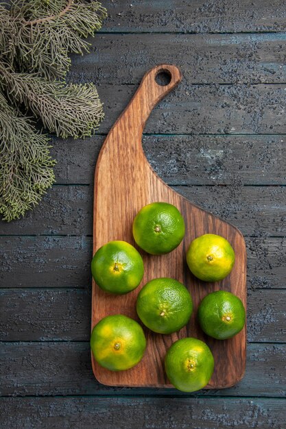 Top view from afar limes and branches limes on the kitchen board next to the tree branches