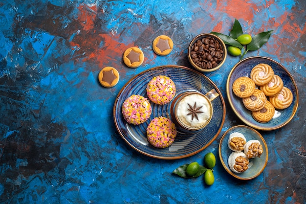 Top view from afar sweets a cup of coffee with cookies coffee beans citrus fruits