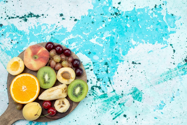 Free photo top view fruit composition sliced and whole with cookies on the bright-blue desk fruit exotic cookie sugar