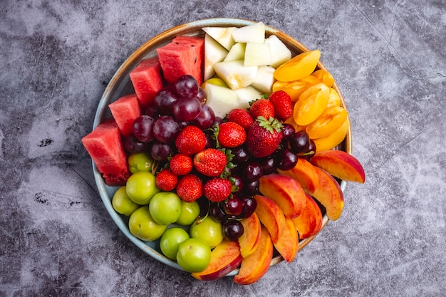 Free photo top view of fruit plate with watermelon greengage plum grape peach apricot strawberry melon and cherry