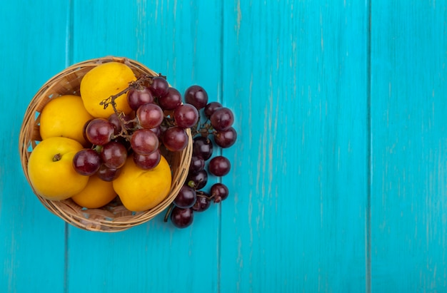 Free Photo top view of fruits as nectacots and grape in basket and on blue background with copy space