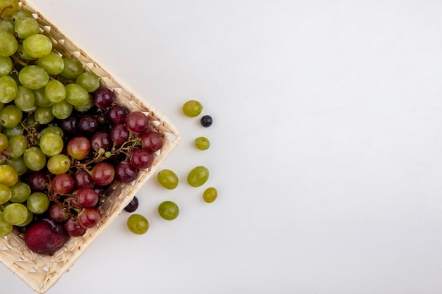 Free photo top view of fruits as pluot and grapes in basket and grape berries on white background with copy space