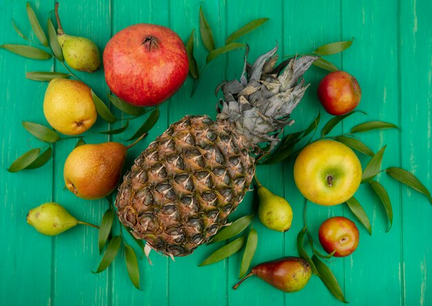 Top view of fruits on green surface decorated with leaves