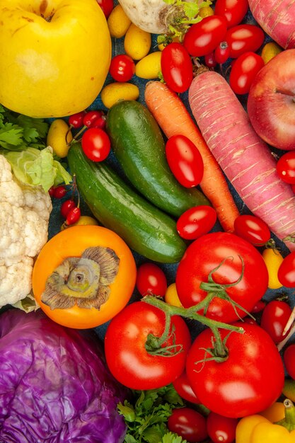 Top view fruits and vegetables carrot cauliflower persimmon radish cherry tomatoes red cabbage tomatoes on blue background