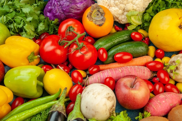 Top view fruits and vegetables eggplant bell peppers apples carrot coriander cauliflower persimmon radish cherry tomatoes on blue background