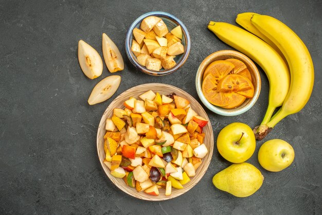 Top view of fruity salad with fresh sliced fruits on the dark-grey background