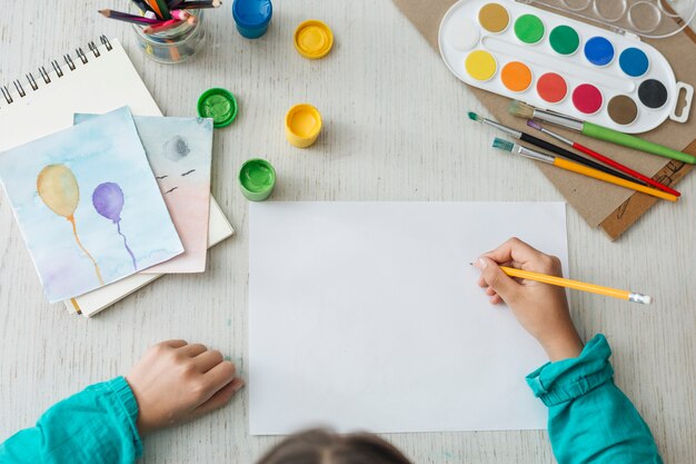 Top view of girl painting with watercolor