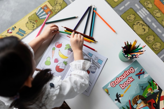 Free photo top view girl with coloring book