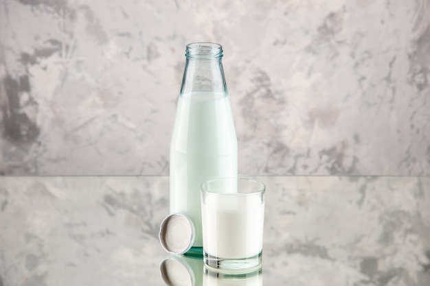 Top view of glass bottle and cup filled with milk cap on pastel colors background with free space