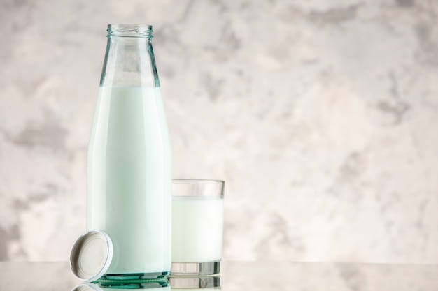 Free photo top view of glass bottle and cup filled with milk cap on white smoke background with free space