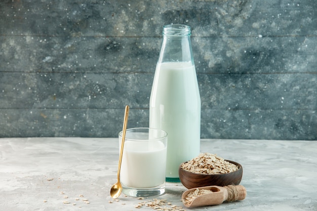 Free photo top view of glass cup and bottle filled with milk and oats inside outside the brown pot on gray background