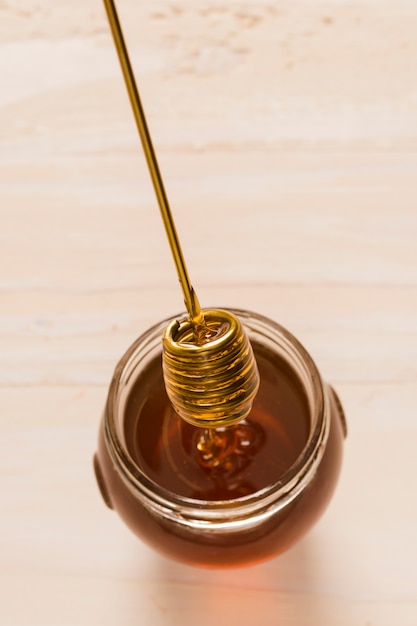 Top view glass jar full of honey with honey spoon