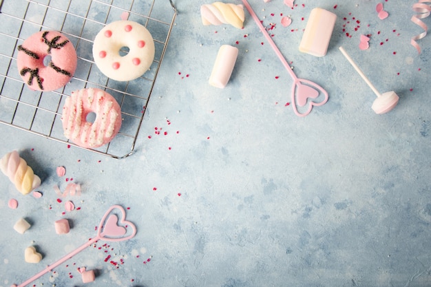 Top view of glazed doughnuts with assortment of candy and marshmallow