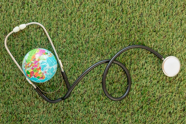 Free photo top view globe with stethoscope on grass