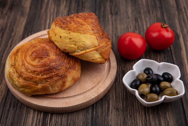 Top view of gogals on a wooden kitchen board with olives on a bowl and fresh tomatoes isolated on a wooden background