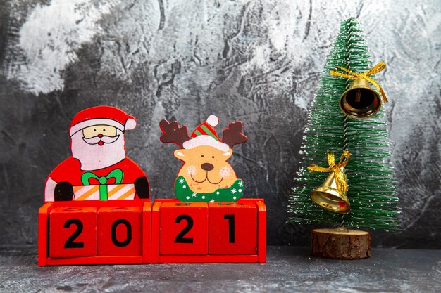 Top view of golden ring bell hanging on pine tree for Christmas holiday and inscription with new year toys on gray background