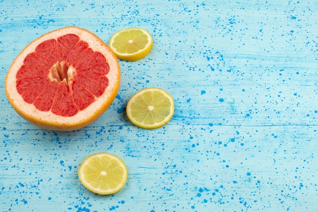 Free photo top view grapefruits and lemons sliced mellow ripe on the bright blue background