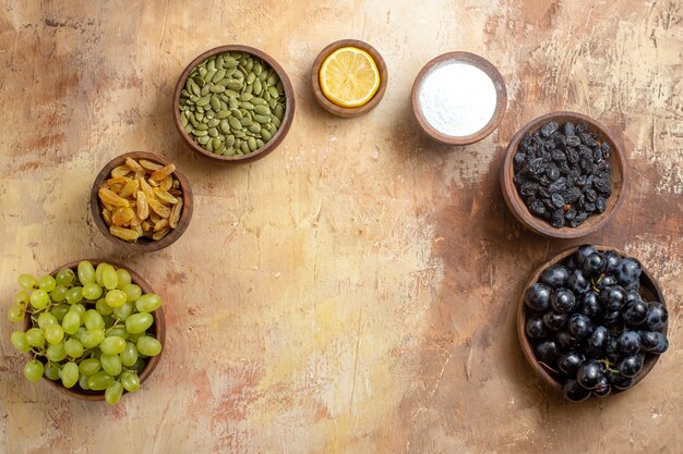 Top view of grapes bowls of grapes pumpkin seeds lemon raisins