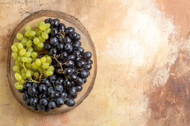 Top view grapes bunches of green and black grapes on the wooden cutting board