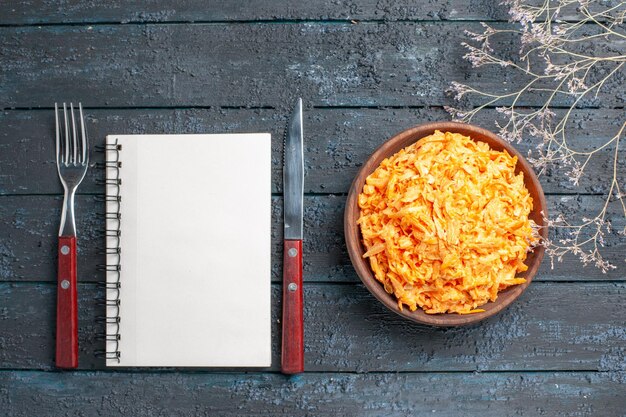 Top view grated carrot salad inside brown plate on the dark-blue rustic desk health salad ripe vegetable diet color