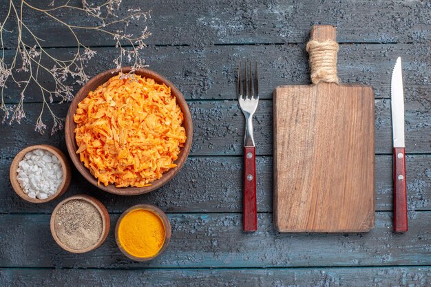 Top view grated carrot salad with garlic and seasonings on dark-blue rustic desk health color salad ripe vegetables diet