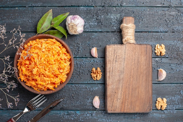 Free Photo top view grated carrot salad with garlic and walnuts on the dark rustic desk health vegetable diet salad color ripe