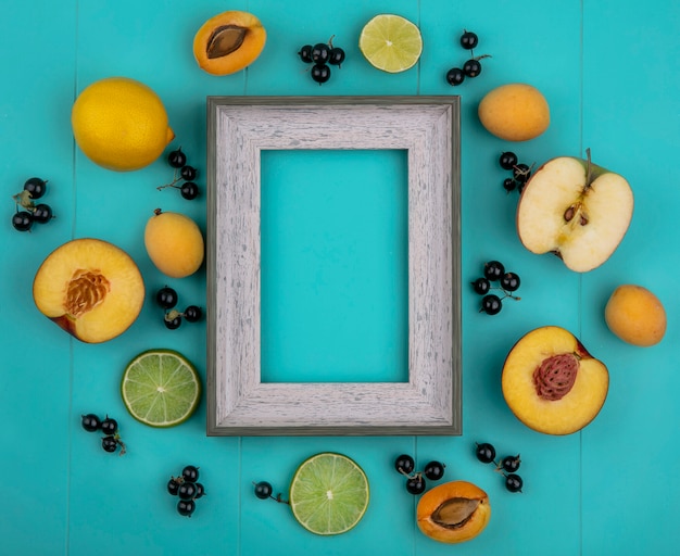 Free Photo top view of gray frame with apricots apples lemon with black currant with lime slices on a light blue surface