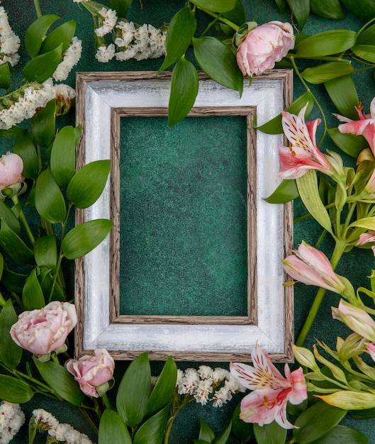 Top view of gray frame with light pink flowers on a green surface